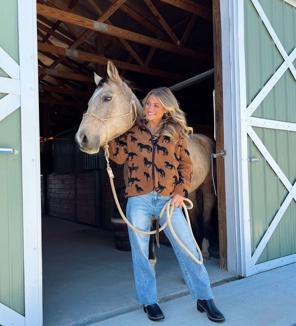 Guest with a buckskin horse at the barn doors